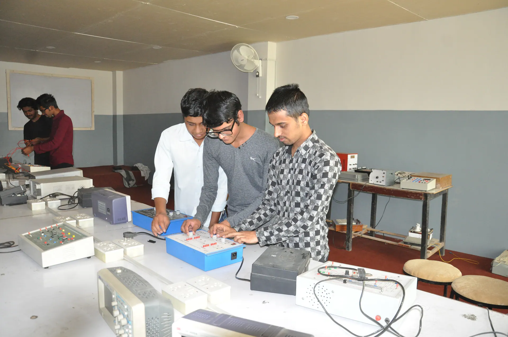 Electronics engineering students testing bench-mounted training equipment