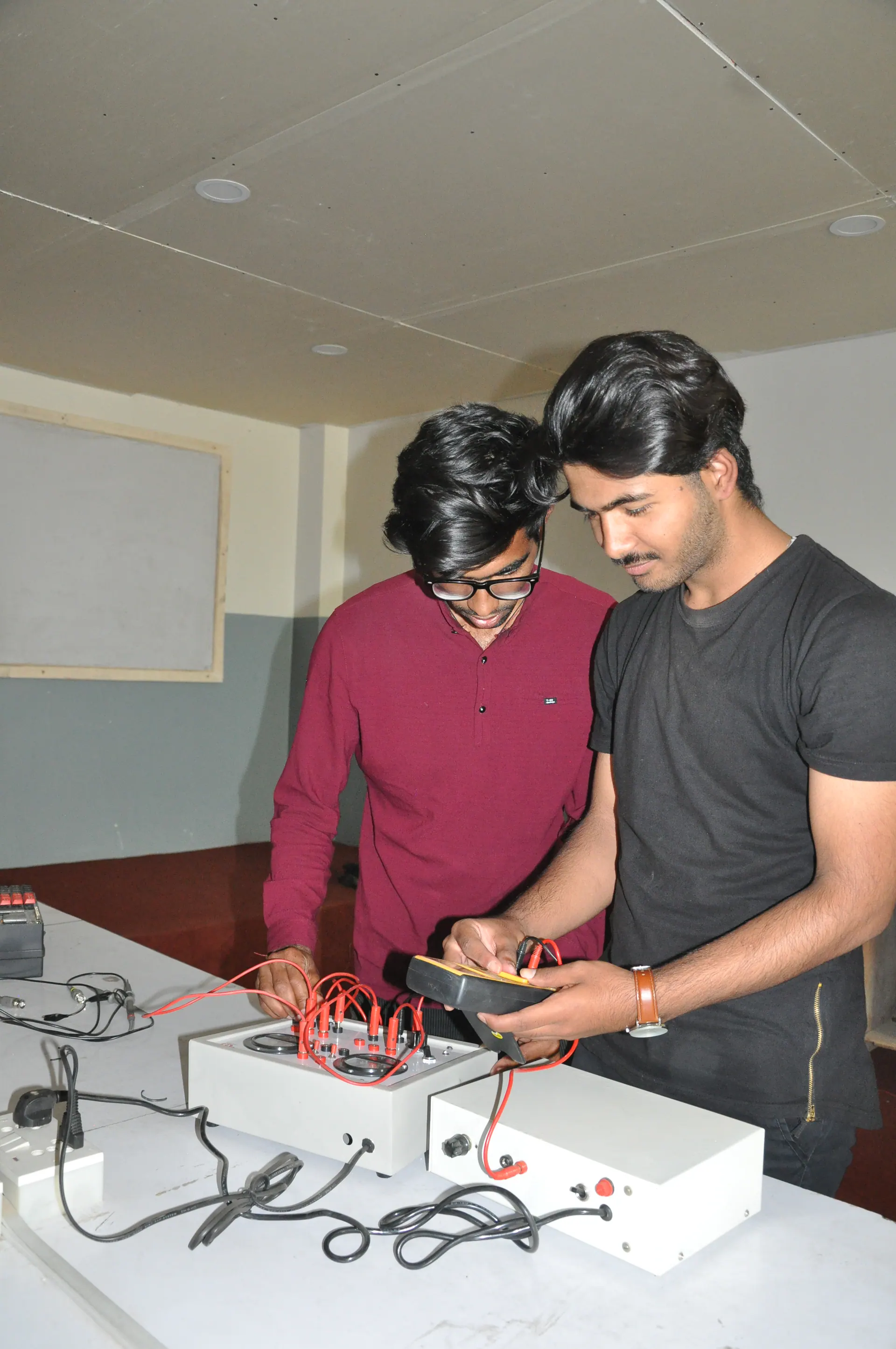 Students measuring a training circuit with probes and a handheld meter