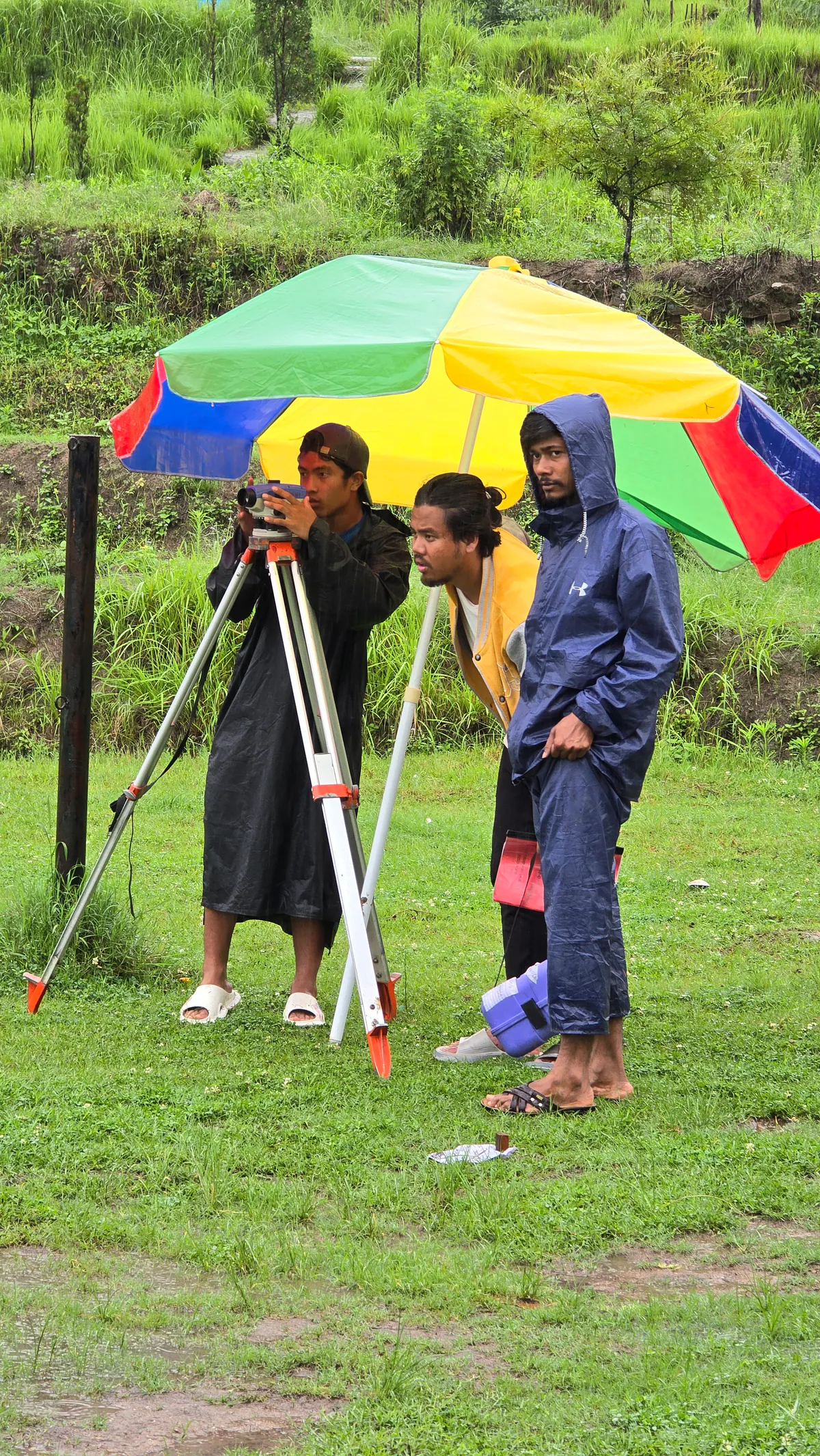 Civil engineering students continuing survey fieldwork in rainy conditions